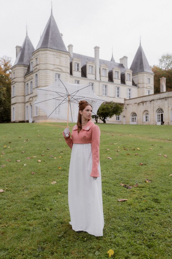 Jeune femme en tenue 1810 Bridgerton dans le parc du château de la Barbelinière